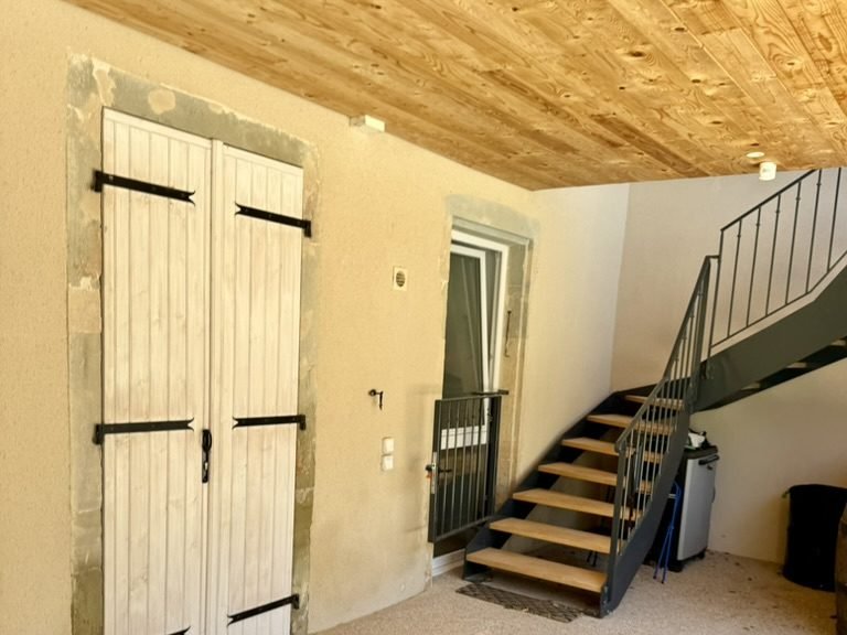 L'entrée du gîte et son escalier, sous le plafond en bois