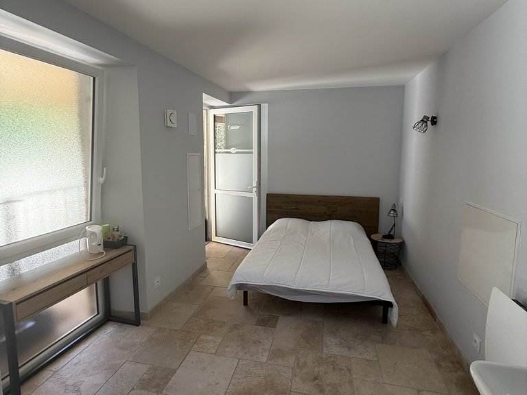Une chambre du gîte : lit double, plan de travail et sol en travertin