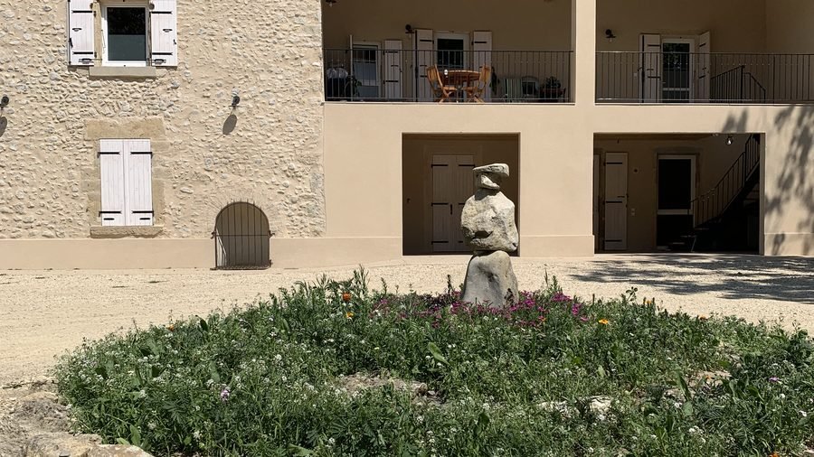 La cour fleurie et son cairn devant la bâtisse en pierre